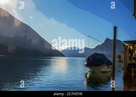 Vue imprenable sur le lac de Lugano et les Alpes suisses. Bateau abritant sur le rivage de nesr d'hiver. Vue depuis Olive Trail Banque D'Images