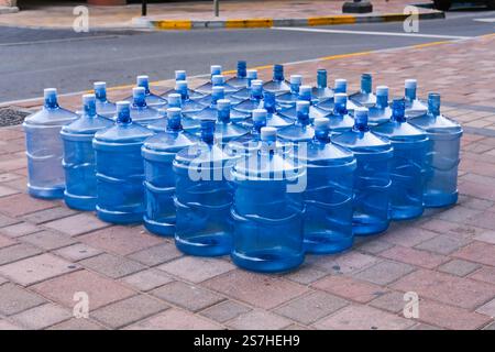 Livraison d'eau dessalée potable embouteillée aux Émirats arabes Unis. Videz les bouteilles d'eau potable en plastique rechargeables placées à l'extérieur du bâtiment résidentiel pour être ramassées. Banque D'Images