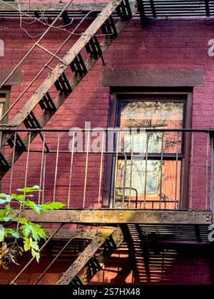 Le feu échappe aux ombres et aux reflets dans la fenêtre sur un bâtiment typique en briques rouges à Greenwich Village, New York City, NY, USA Banque D'Images