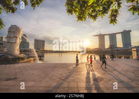 Découvrez le coucher de soleil enchanteur sur Marina Bay à Singapour, avec l'emblématique Merlion et la ligne d'horizon, parfait pour les amateurs de voyage et de photographie Banque D'Images