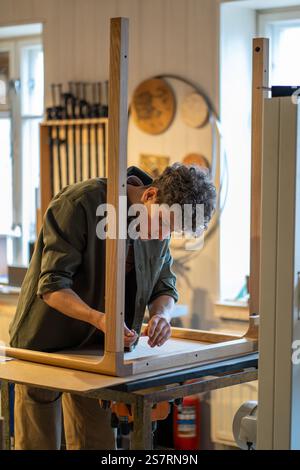 Craftsman attache les pieds à la base de la table, complétant l'assemblage en atelier. Travail manuel, bois durable Banque D'Images
