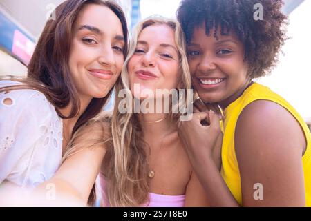 Trois jeunes femmes heureuses prenant un selfie ensemble dans une rue de la ville Banque D'Images