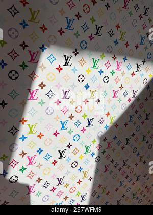 Logo Louis Vuitton coloré au motif monogramme. Lumière et ombre sur le papier peint. LV artistique, vue verticale. Logo de mode reconnu mondialement célèbre Banque D'Images