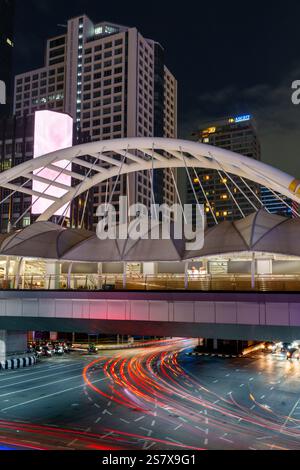 Vue nocturne sur le pont Chong Nonsi à Bangkok, avec sa passerelle éclairée et ses feux de circulation vibrants en contrebas, mettant en valeur la dynamique urbaine de la ville Banque D'Images