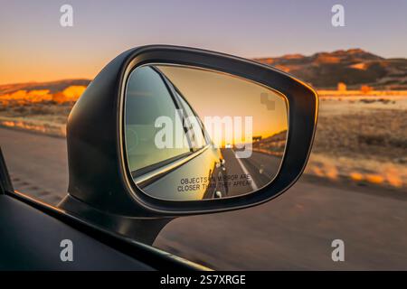 Reflet du ciel du coucher du soleil dans un rétroviseur de voiture le long de l'autoroute, Arizona, USA Banque D'Images