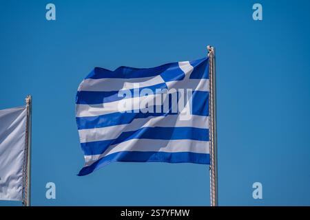 Drapeau grec soufflant dans le vent avec le ciel bleu derrière Banque D'Images