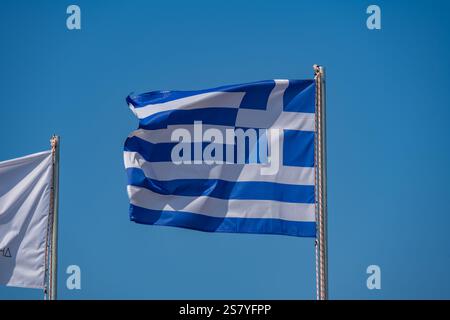 Drapeau grec soufflant dans le vent avec le ciel bleu derrière Banque D'Images