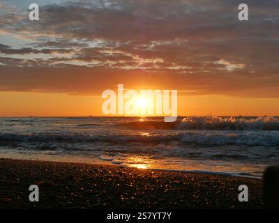 Vue sur un coucher de soleil romantique sur la mer. Le jeu de lumière du soleil couchant crée une scène captivante et atmosphérique Banque D'Images