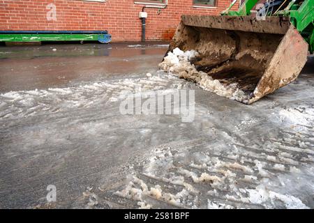 Une pelle verte est dans la neige. La neige est blanche et la pelle est sale. La pelle est utilisée pour déneiger Banque D'Images