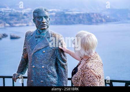 Nerja Espagne. Un touriste admire la statue du roi Alphonse XII sur la Balcón de Europa à Nerja en Espagne baignée de soleil de fin de soirée Banque D'Images