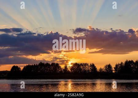 nuages de différentes couleurs pendant le coucher du soleil sur la rive d'un lac, un lac avec de l'eau colorée dans la couleur du coucher du soleil dans la saison estivale Banque D'Images