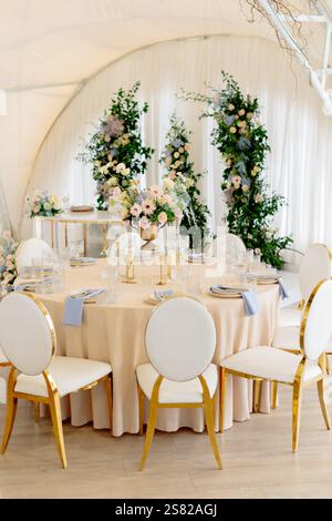 Table de Présidium décorée avec des fleurs de couleur pastel dans une tente de chapiteau de mariage crée une atmosphère romantique et élégante Banque D'Images