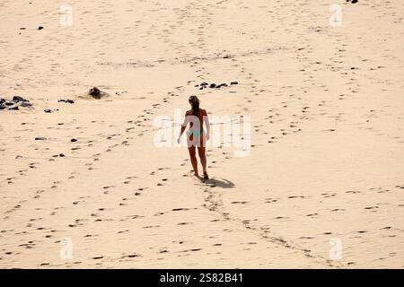 Jeune femme dans un petit bikini vert sur la plage à El Cotillo, Fuerteventura. Prise en décembre 2024. Banque D'Images