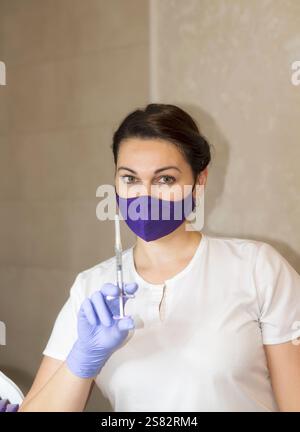 docteur en masque sur le visage tient la seringue devant lui Banque D'Images