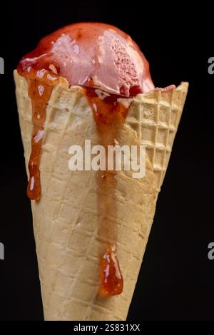 crème glacée aromatisée à la framboise avec des baies de framboise rouges et de la confiture de baies fraîches sur un fond noir, gros plan de crème glacée aromatisée aux baies avec une râpe fraîche Banque D'Images