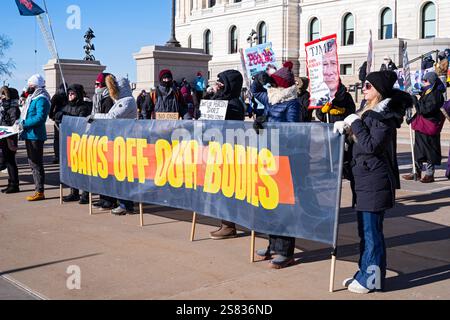 ST. PAUL, MN, États-Unis - 18 JANVIER 2025 : les participants derrière le podium des conférenciers tiennent des pancartes pour rallier les supporters lors de la manifestation populaire au capitole de l’État. Banque D'Images