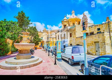 La vieille fontaine en pierre dans le petit jardin de la rue College avec une vue sur le dôme de l'église St Paul, Rabat, Malte Banque D'Images
