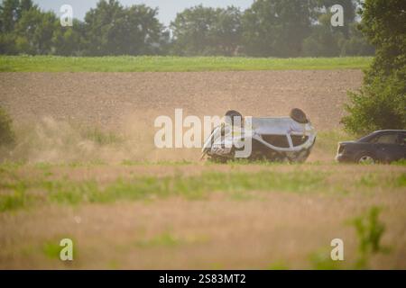 Une voiture s'est écrasée dans un champ de saleté. La voiture est à l'envers et a beaucoup de saleté dessus Banque D'Images