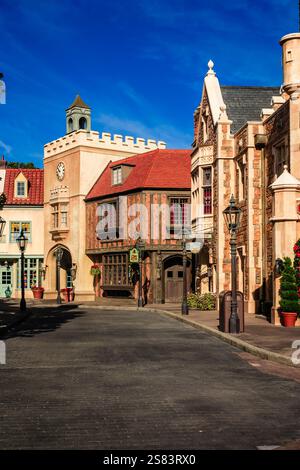 Une scène de rue avec une tour de l'horloge et un bâtiment avec un toit rouge. La rue est bordée de commerces et un banc est situé au milieu de la rue Banque D'Images