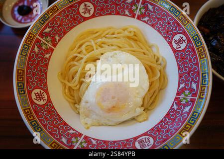 Spaghetti avec oeuf frit sur une assiette dans un restaurant chinois. Banque D'Images