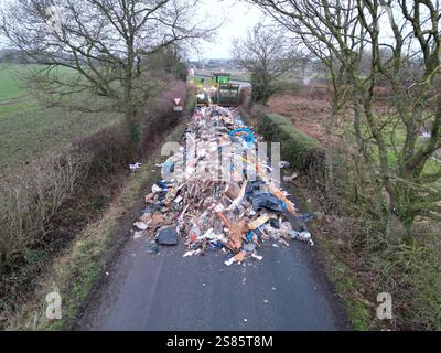Les entrepreneurs travaillent à enlever le tas de déchets de 10 pieds de haut de Watery Lane, à la périphérie de Lichfield dans le Staffordshire. Les autorités locales recherchent des preuves vidéo pour retrouver les mouches qui ont déversé un énorme monticule de déchets de construction s'étendant sur plus de 40 pieds le long d'une route à deux voies, bloquant l'accès aux maisons et aux entreprises. Date de la photo : mardi 21 janvier 2025. Banque D'Images