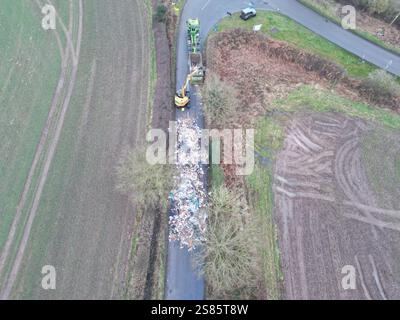 Les entrepreneurs travaillent à enlever le tas de déchets de 10 pieds de haut de Watery Lane, à la périphérie de Lichfield dans le Staffordshire. Les autorités locales recherchent des preuves vidéo pour retrouver les mouches qui ont déversé un énorme monticule de déchets de construction s'étendant sur plus de 40 pieds le long d'une route à deux voies, bloquant l'accès aux maisons et aux entreprises. Date de la photo : mardi 21 janvier 2025. Banque D'Images