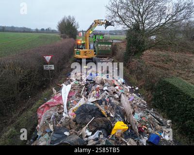 Les entrepreneurs travaillent à enlever le tas de déchets de 10 pieds de haut de Watery Lane, à la périphérie de Lichfield dans le Staffordshire. Les autorités locales recherchent des preuves vidéo pour retrouver les mouches qui ont déversé un énorme monticule de déchets de construction s'étendant sur plus de 40 pieds le long d'une route à deux voies, bloquant l'accès aux maisons et aux entreprises. Date de la photo : mardi 21 janvier 2025. Banque D'Images