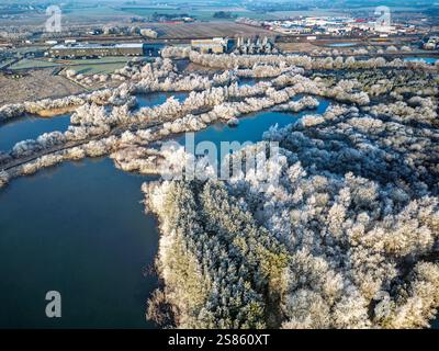 Une belle vue à vol d'oiseau représentant un paysage hivernal glacial avec des arbres enneigés le long d'un chemin de terre entouré de lacs gelés, mettant l'accent sur natu Banque D'Images