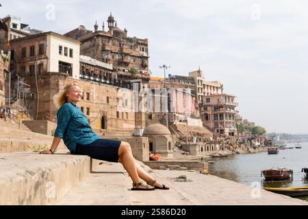 Femme blonde explorant le front de mer de la ville antique de Varanasi. Profiter de la journée ensoleillée sur la promenade du Gange en Uttar Pradesh, Inde Banque D'Images