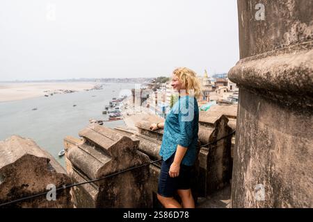 Jeune femme debout sur le toit de la mosquée surplombant la vieille ville de Varanasi et le fleuve Gange dans l'Uttar Pradesh, Inde. Banque D'Images