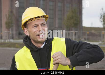 Travailleur de la construction souriant dans le casque jaune, Allemagne, Europe Banque D'Images