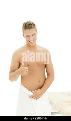 Jeune homme beau blond enveloppé dans une serviette montrant le pouce vers le haut, Danemark, Europe Banque D'Images