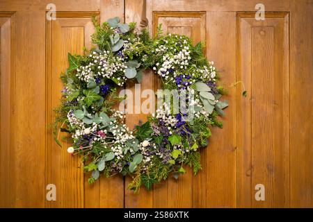 Couronne de porte avant. Classique toute l'année faux eucalyptus fait à la main, lierre commun, genévrier et couronne de gypsophila sur fond en bois. Banque D'Images