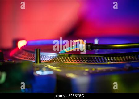 Platine vinyle avec détails d'enregistrement en basse lumière. Disque vinyle sur fond rouge et bleu de platine. Détail de l'aiguille du plateau tournant sur dossier. Banque D'Images
