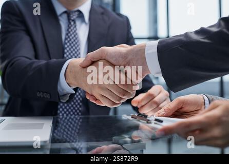 Des hommes d'affaires ou des avocats qui se secouent la main pour terminer la réunion ou la négociation dans un bureau ensoleillé. Liaison et partenariat commerciaux Banque D'Images