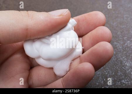 Mousse à raser sur une main sur un fond sombre Banque D'Images