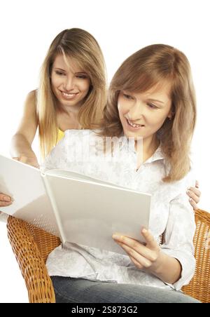 Deux jolies filles blondes souriantes lisant un livre, isolées sur fond blanc, Fédération de Russie Banque D'Images