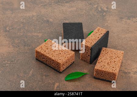 Ensemble d'éponges pour laver la vaisselle. Concept de nettoyage biologique, arôme de café. Style zéro déchet, fond de pierre marron chaud, pose plate, espace de copie Banque D'Images
