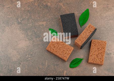 Ensemble d'éponges pour laver la vaisselle. Concept de nettoyage biologique, arôme de café. Style zéro déchet, fond de pierre marron chaud, pose plate, vue de dessus Banque D'Images
