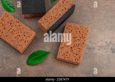 Ensemble d'éponges pour laver la vaisselle. Concept de nettoyage biologique, arôme de café. Style zéro déchet, fond de pierre marron chaud, pose plate, vue de dessus Banque D'Images