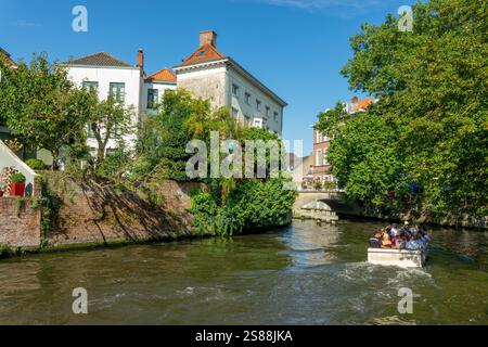 Touristes dans un bateau sur un canal, excursion touristique en bateau fluvial à Bruges, Belgique Banque D'Images