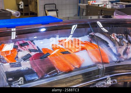 Des filets de saumon frais et du poisson entier sur glace dans les fruits de mer exposés au marché sous des lumières vives. Suède. Banque D'Images