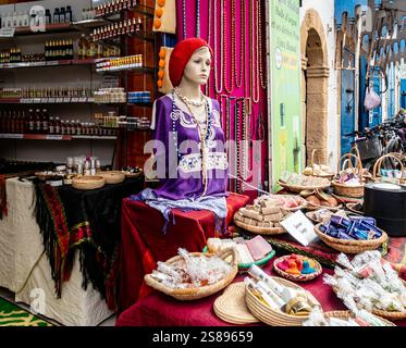 Un étal coloré du marché présente des objets artisanaux faits à la main, des herbes, des savons et des vêtements traditionnels dans le souk d'Essaouira, au Maroc. Banque D'Images