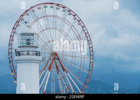 Batumi, Géorgie - 13 JUIN 2024 : Grande roue et phare situés au Miracle Park le long de la côte de Batumi, Géorgie. Banque D'Images