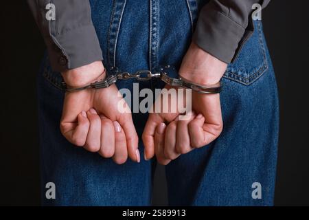 Femme en menottes métalliques sur fond noir, gros plan Banque D'Images