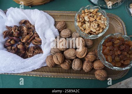 Produits crétois fins sur un plateau de service vintage : figues séchées, noix en coquille, noix pelées et raisins secs dans des bols en verre Banque D'Images