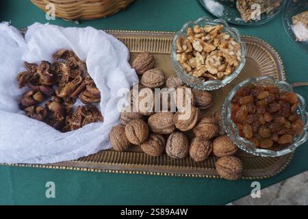 Produits crétois fins sur un plateau de service vintage : figues séchées, noix en coquille, noix pelées et raisins secs dans des bols en verre Banque D'Images