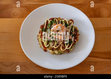 Okonomiyaki. Sur une assiette avec des crevettes, de la nourriture japonaise. Banque D'Images