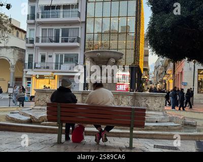 Deux vieilles femmes avec leur chien sont assis sur un banc devant la fontaine Morosini ou Lions à Héraklion pendant la saison des soldes d'hiver Banque D'Images