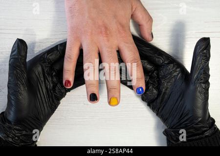 Manucure en cours - de beaux ongles d'homme manucurés avec vernis à ongles rouge. L'industrie de la beauté et des soins des ongles, salons de beauté Banque D'Images